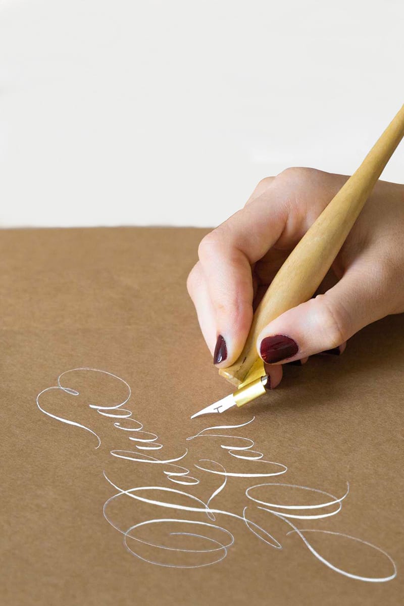 Mână scriind caligrafie cu penița pe hârtie kraft