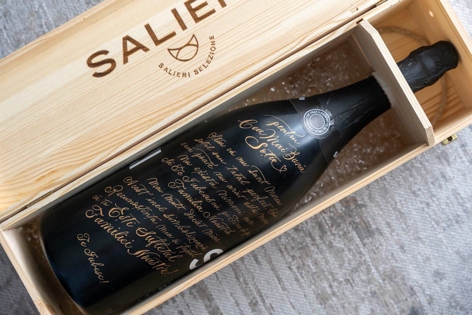 Sticlă de vin gravată cu caligrafie aurie, în cutie de lemn